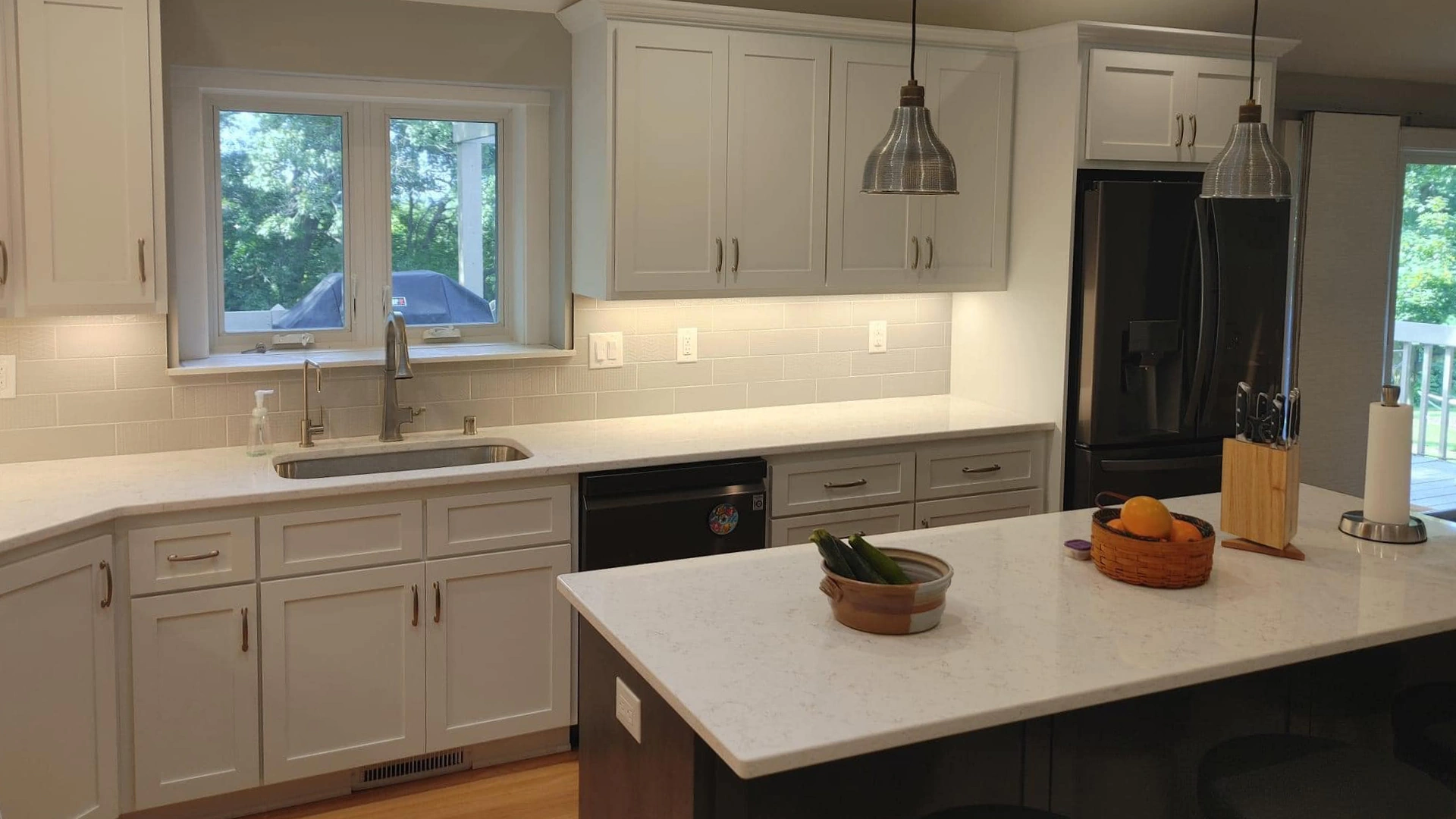 newly renovated kitchen of residential house with white cabinets and hanging lights at kitchen countertop
